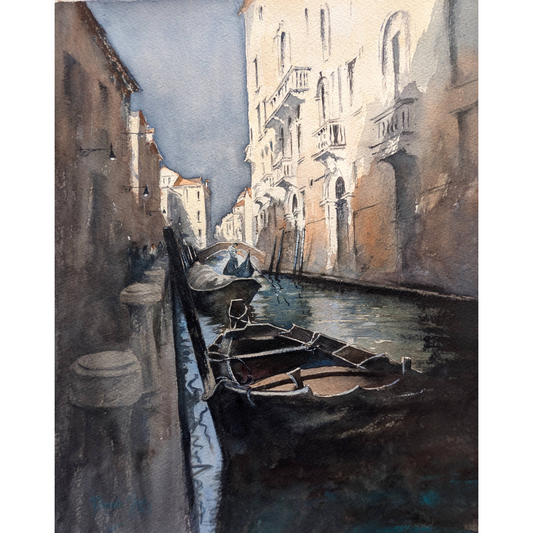 Evening lights shining on building in a Venice canal with boats in the shadows.
